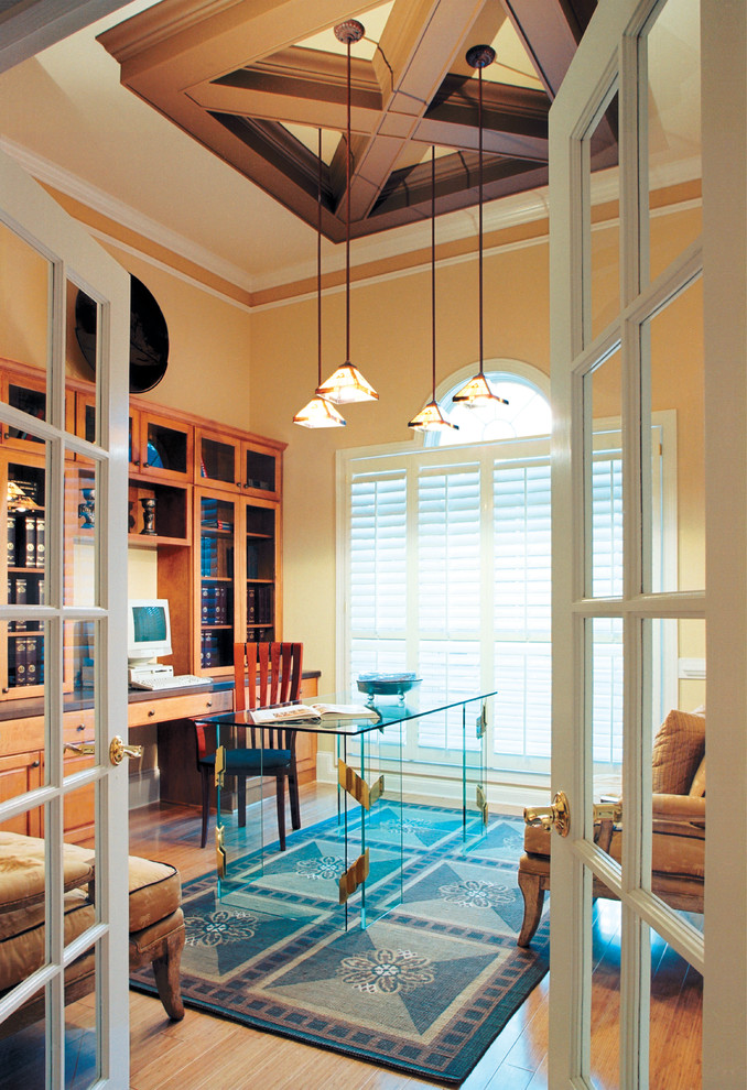 Imagen de despacho clásico sin chimenea con suelo de madera clara, escritorio independiente y parades naranjas