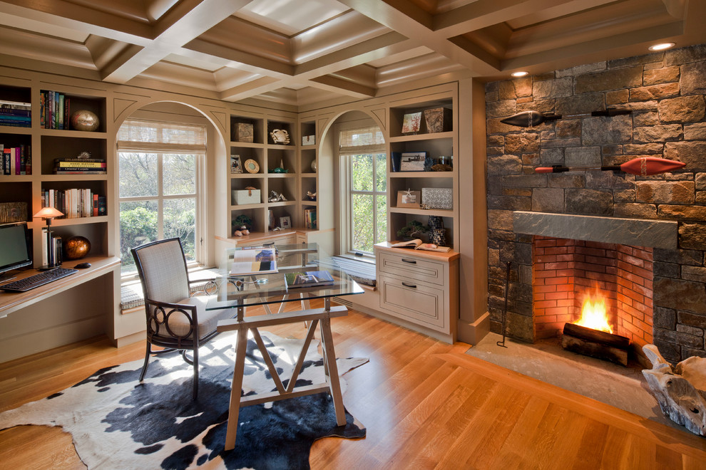 Imagen de despacho tradicional con todas las chimeneas, marco de chimenea de piedra y escritorio independiente