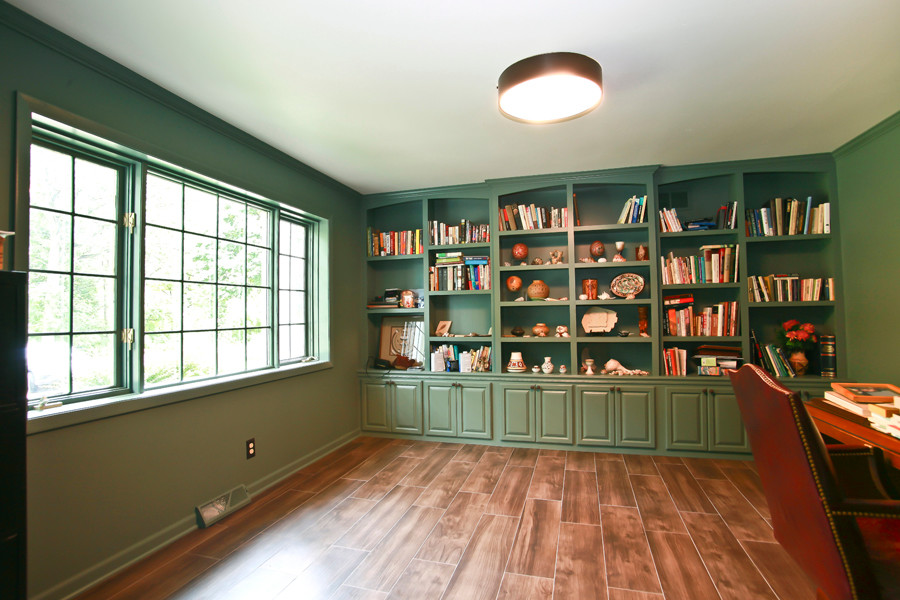 Klassisk inredning av ett mycket stort hemmabibliotek, med gröna väggar, vinylgolv och ett fristående skrivbord