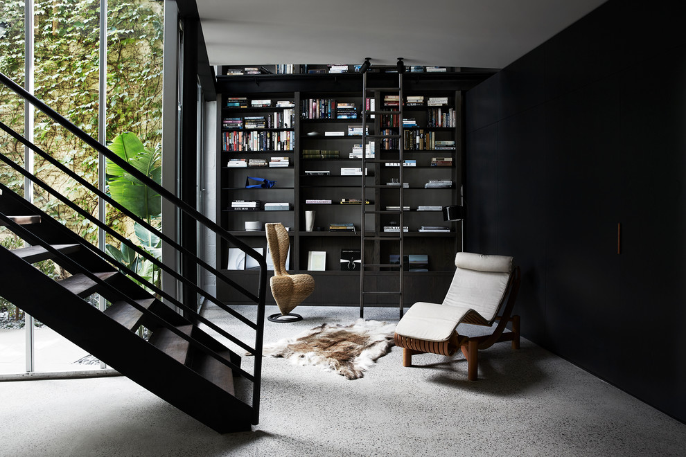 На фото: домашняя библиотека в современном стиле с черными стенами, бетонным полом и серым полом