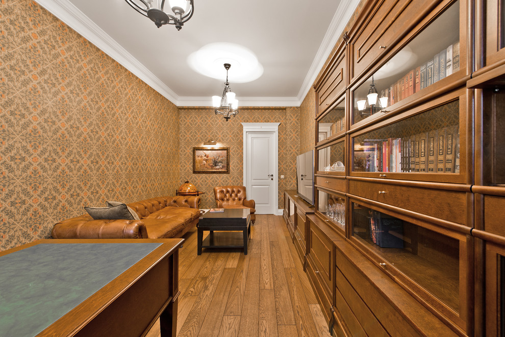 Klassisches Arbeitszimmer ohne Kamin mit oranger Wandfarbe, braunem Holzboden und freistehendem Schreibtisch in Sonstige