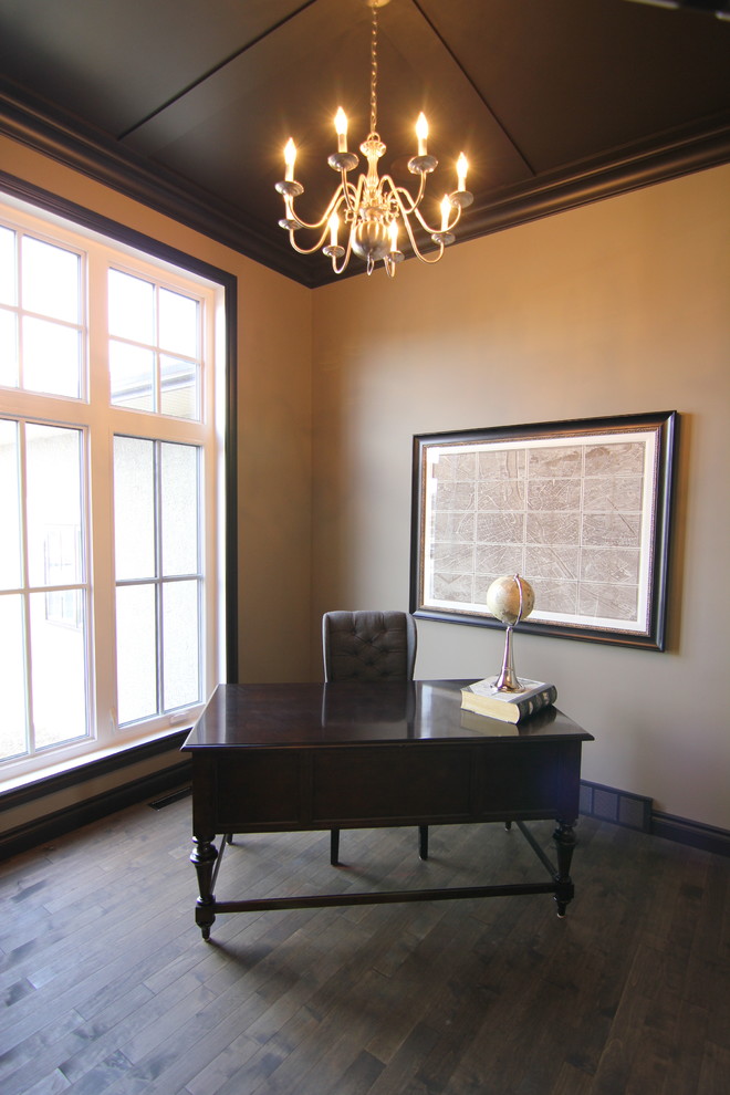 Ejemplo de despacho tradicional renovado pequeño con paredes beige, suelo de madera oscura y escritorio independiente