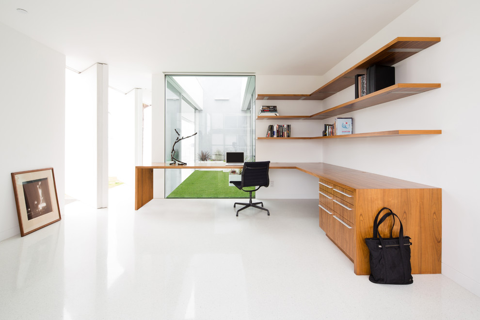 Diseño de despacho minimalista de tamaño medio con paredes blancas, escritorio empotrado y suelo blanco