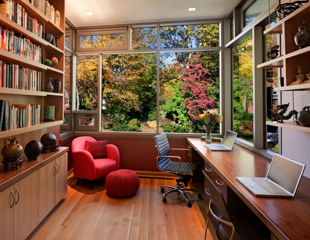 На фото: домашняя библиотека среднего размера в современном стиле с паркетным полом среднего тона, встроенным рабочим столом и коричневым полом без камина с