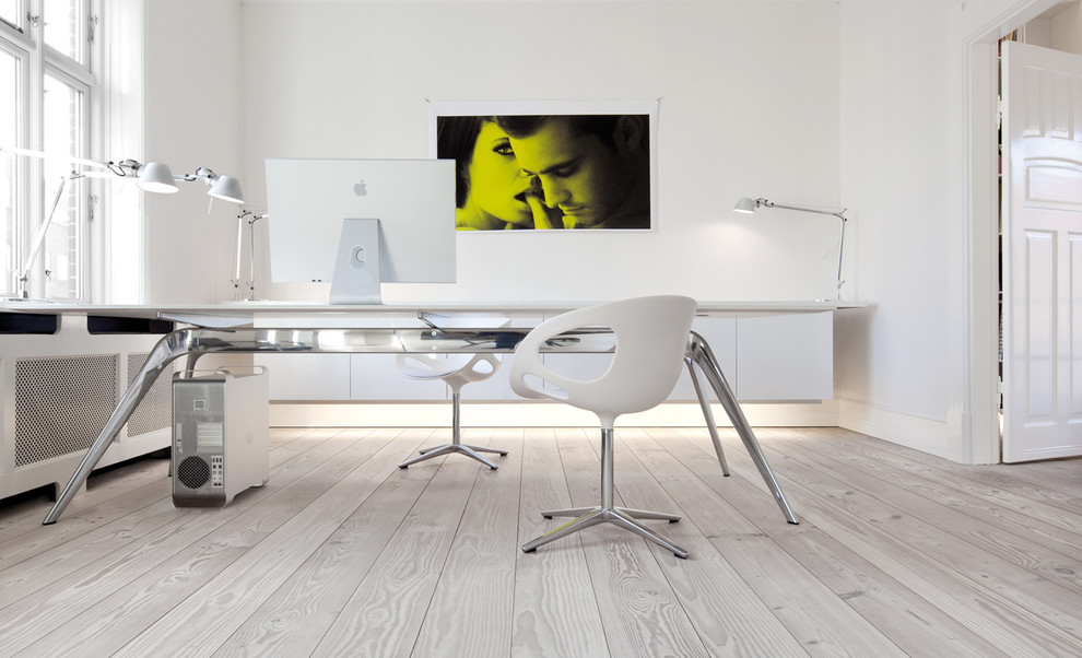 Exempel på ett minimalistiskt arbetsrum, med vita väggar, ljust trägolv och ett fristående skrivbord