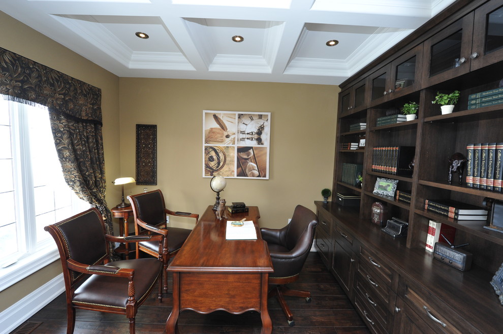 Bild på ett vintage arbetsrum, med ett bibliotek, beige väggar, mörkt trägolv, ett fristående skrivbord och brunt golv