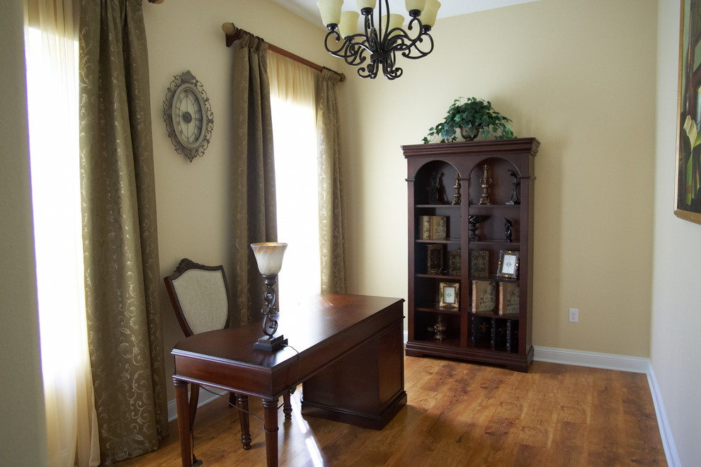 Diseño de despacho tradicional de tamaño medio con paredes beige, suelo de madera en tonos medios, escritorio independiente y suelo marrón