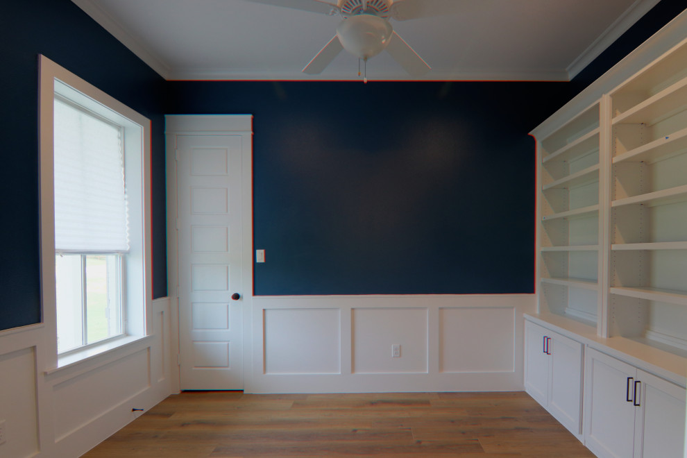 Foto på ett mellanstort lantligt hemmabibliotek, med blå väggar, vinylgolv, ett fristående skrivbord och brunt golv