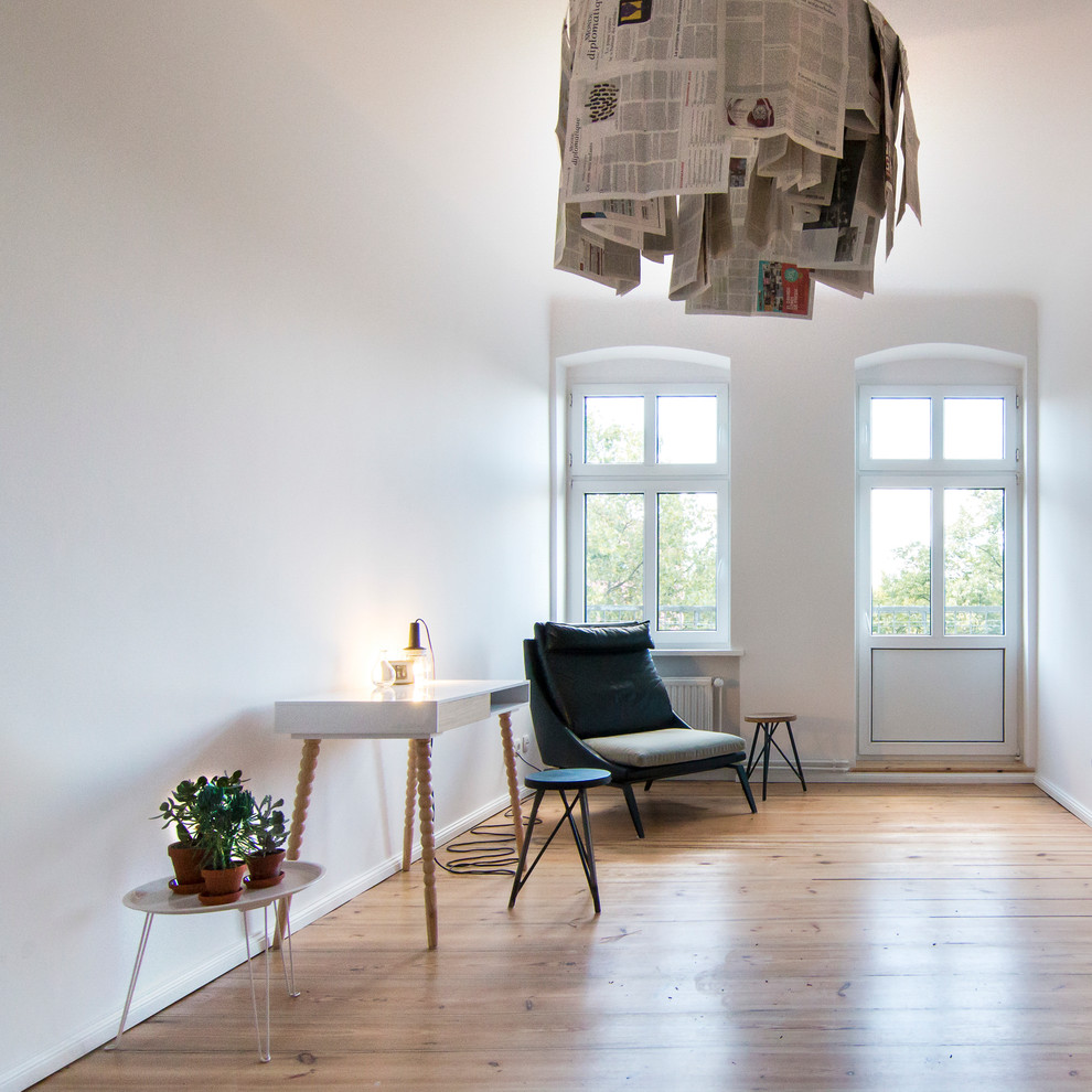 Mittelgroßes Modernes Arbeitszimmer ohne Kamin mit weißer Wandfarbe, braunem Holzboden und freistehendem Schreibtisch in Berlin