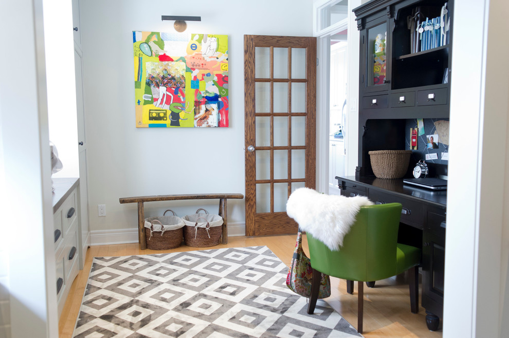 Diseño de despacho clásico renovado de tamaño medio con paredes blancas, suelo de madera clara y escritorio independiente