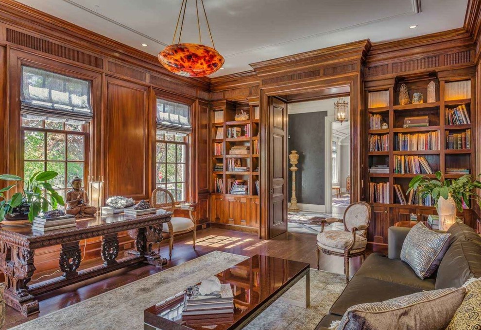 Cette photo montre un grand bureau chic avec une bibliothèque ou un coin lecture, un mur marron, parquet foncé, une cheminée standard, un manteau de cheminée en pierre, un bureau indépendant et un sol marron.