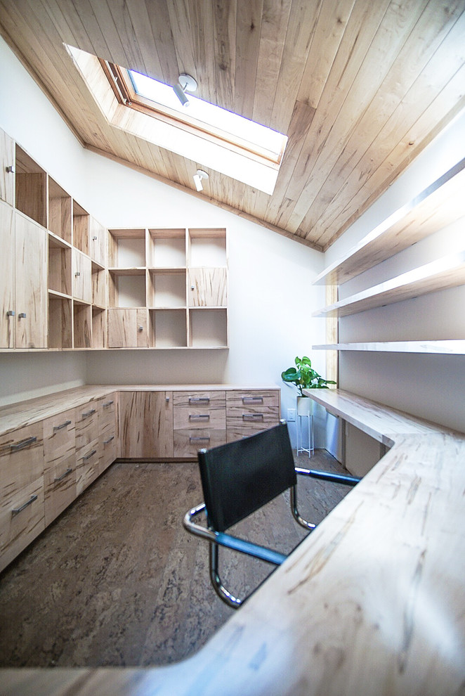 Foto på ett mellanstort funkis hemmastudio, med vita väggar, korkgolv, ett inbyggt skrivbord och brunt golv
