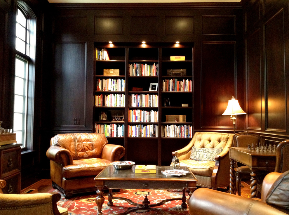 Imagen de despacho clásico grande con biblioteca, paredes marrones, suelo de madera en tonos medios y suelo marrón