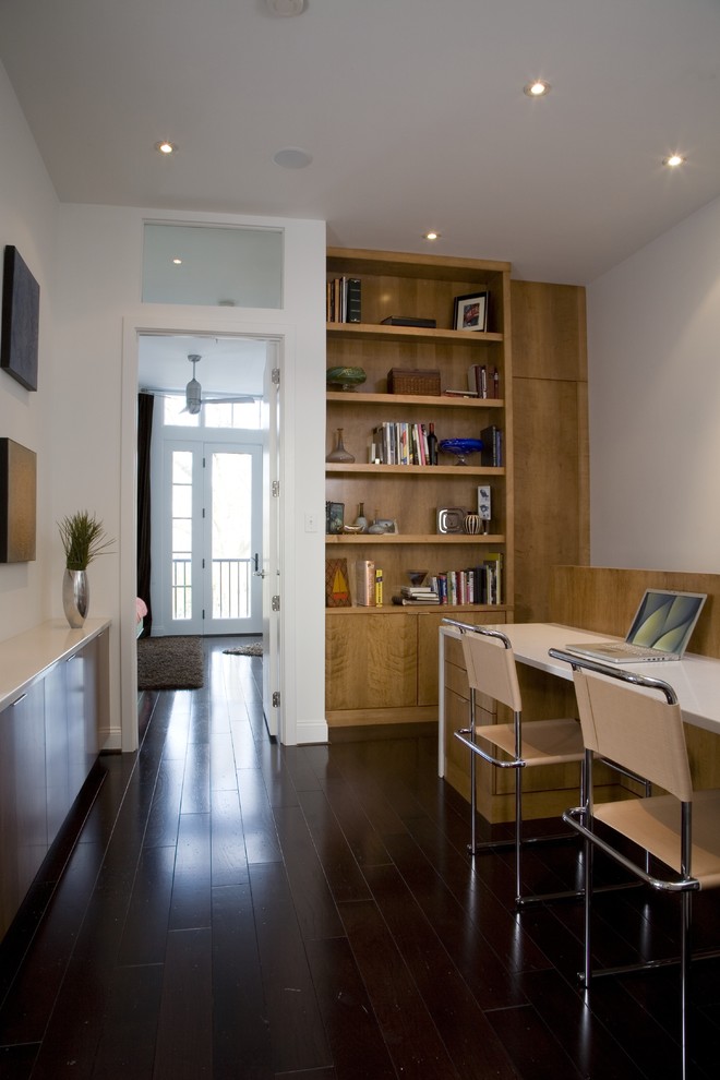 Diseño de despacho contemporáneo con paredes blancas, suelo de madera oscura, escritorio empotrado y suelo negro
