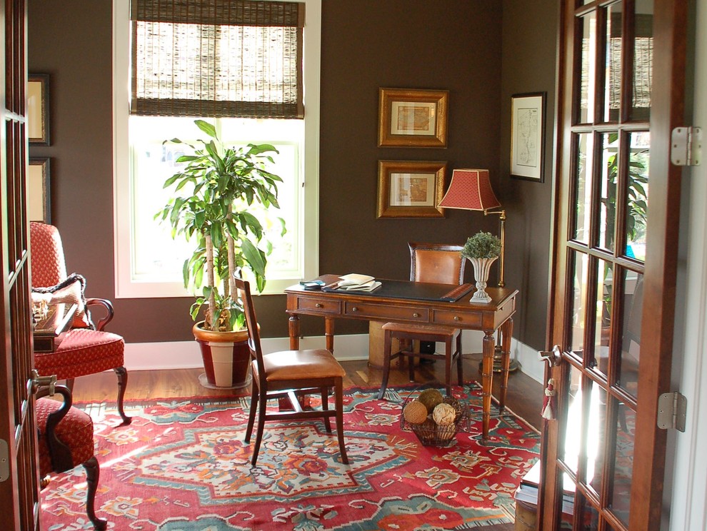 Mittelgroßes Klassisches Arbeitszimmer mit Arbeitsplatz, brauner Wandfarbe, dunklem Holzboden, freistehendem Schreibtisch und braunem Boden in Denver