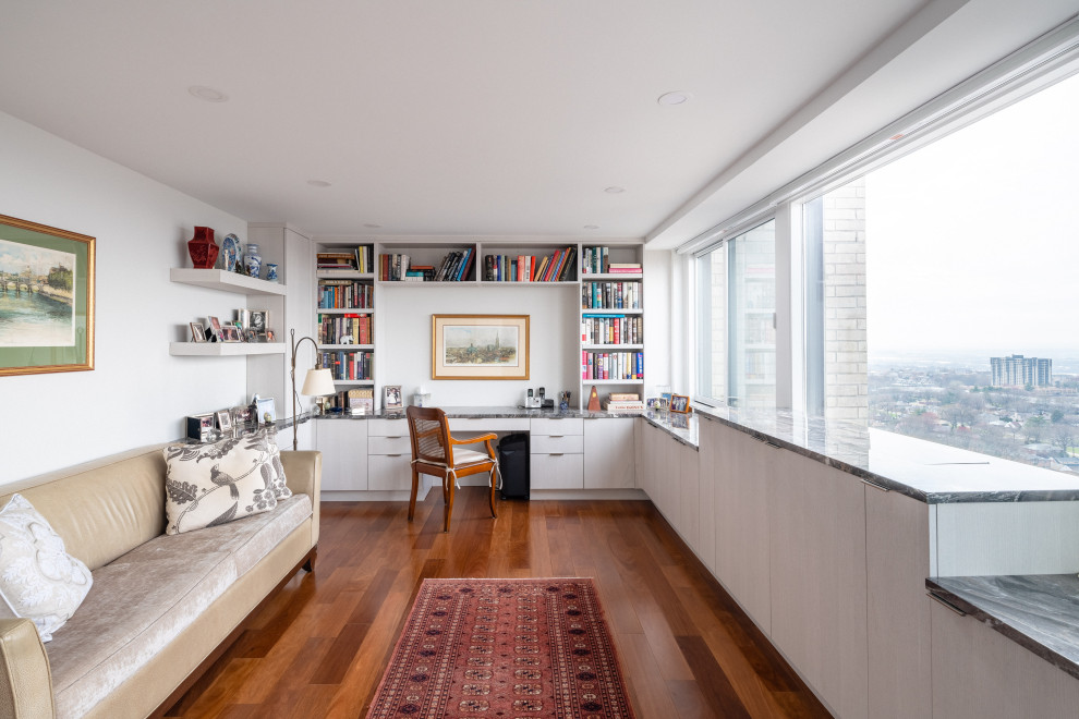 Modernes Arbeitszimmer mit weißer Wandfarbe, braunem Holzboden, Einbau-Schreibtisch und braunem Boden in New York