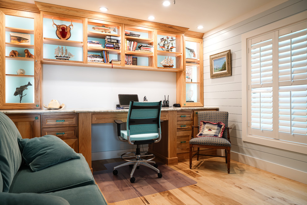 Inspiration för små maritima hemmabibliotek, med vita väggar, ljust trägolv, ett inbyggt skrivbord och brunt golv