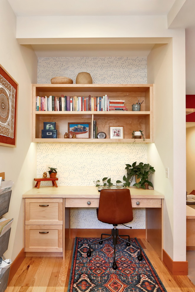 Foto på ett rustikt hemmabibliotek, med vita väggar, ett inbyggt skrivbord, mellanmörkt trägolv och brunt golv