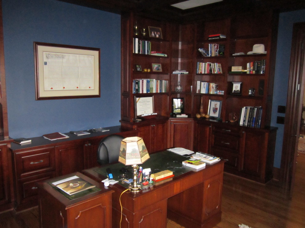 Modelo de despacho clásico de tamaño medio sin chimenea con paredes azules, suelo de madera en tonos medios y escritorio independiente
