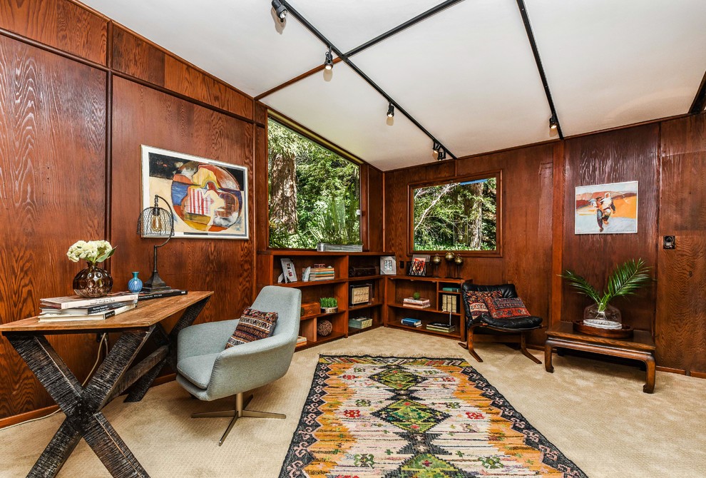Foto på ett stort 60 tals hemmabibliotek, med bruna väggar, heltäckningsmatta, ett fristående skrivbord och beiget golv
