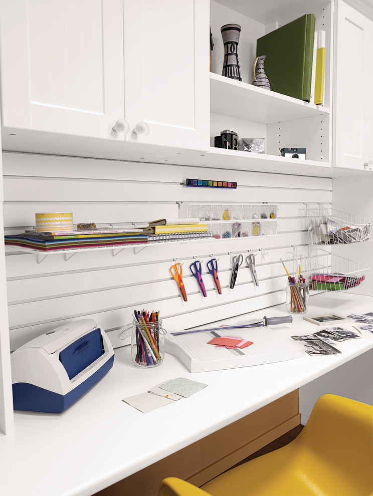 Cette photo montre un bureau atelier tendance de taille moyenne avec un sol en bois brun, aucune cheminée, un bureau intégré et un mur blanc.
