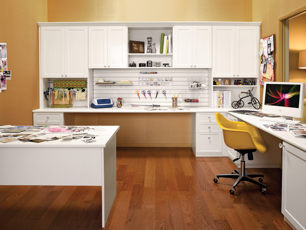 Foto di una stanza da lavoro design di medie dimensioni con pavimento in legno massello medio, nessun camino, pareti gialle e scrivania incassata