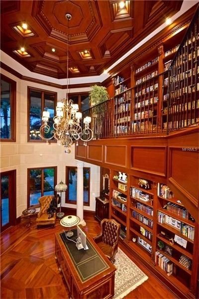 На фото: огромный домашняя библиотека в классическом стиле с коричневыми стенами, паркетным полом среднего тона, фасадом камина из камня и отдельно стоящим рабочим столом с