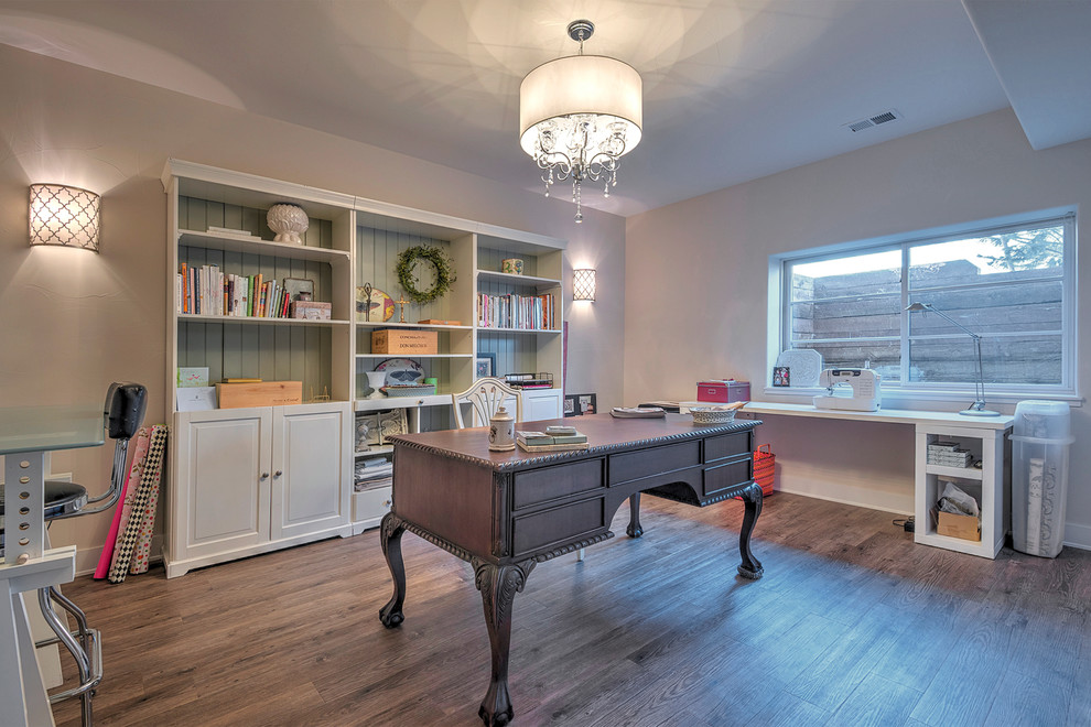 Mittelgroßes Klassisches Arbeitszimmer ohne Kamin mit Studio, beiger Wandfarbe, braunem Holzboden, freistehendem Schreibtisch und braunem Boden in Denver