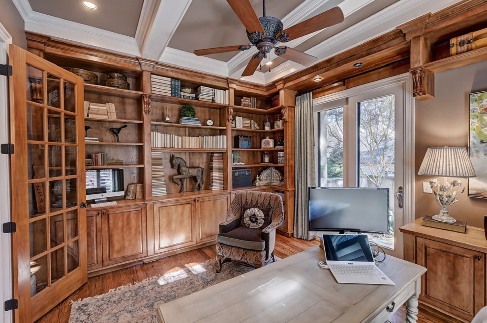 Imagen de despacho de tamaño medio sin chimenea con biblioteca, paredes marrones, suelo de madera en tonos medios, escritorio independiente, suelo marrón y vigas vistas