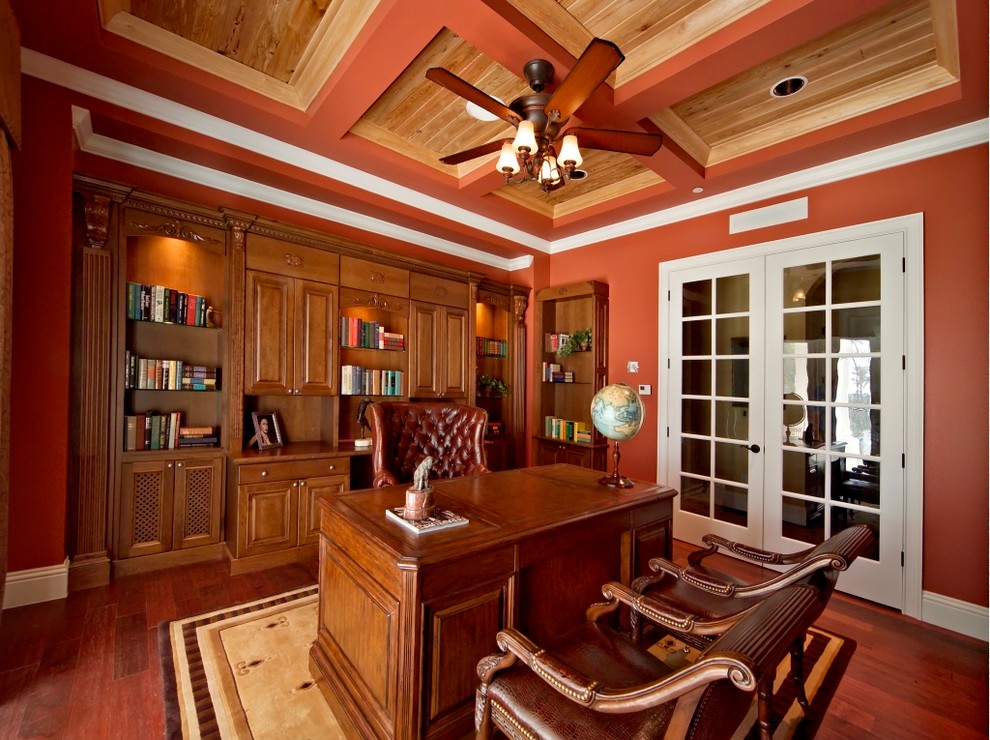 This is an example of a large modern study in San Francisco with red walls, dark hardwood flooring, no fireplace, a freestanding desk and brown floors.