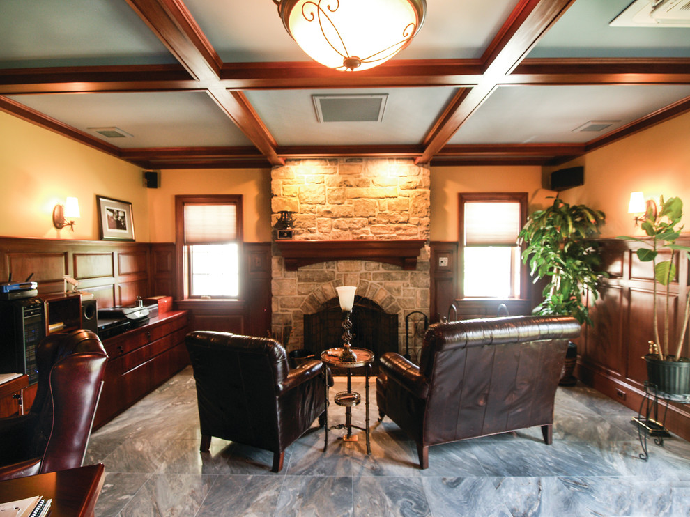 Ejemplo de despacho tradicional de tamaño medio con paredes beige, suelo de baldosas de porcelana, todas las chimeneas, marco de chimenea de piedra, escritorio empotrado y suelo gris