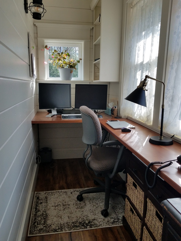 Idee per un piccolo studio country con pareti bianche, pavimento in laminato, scrivania incassata, pavimento marrone, soffitto a volta e pareti in perlinato