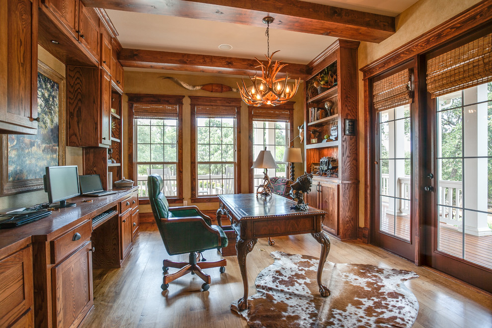 Ejemplo de despacho campestre grande con paredes beige, suelo de madera en tonos medios y escritorio independiente
