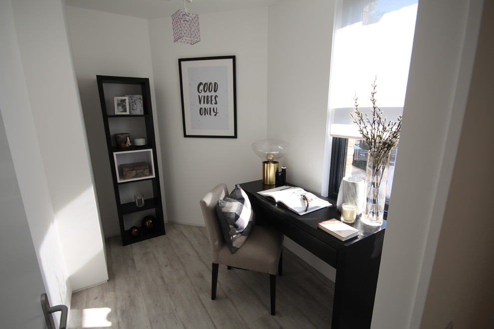 This is an example of a small contemporary home office in London with white walls, a freestanding desk and grey floors.