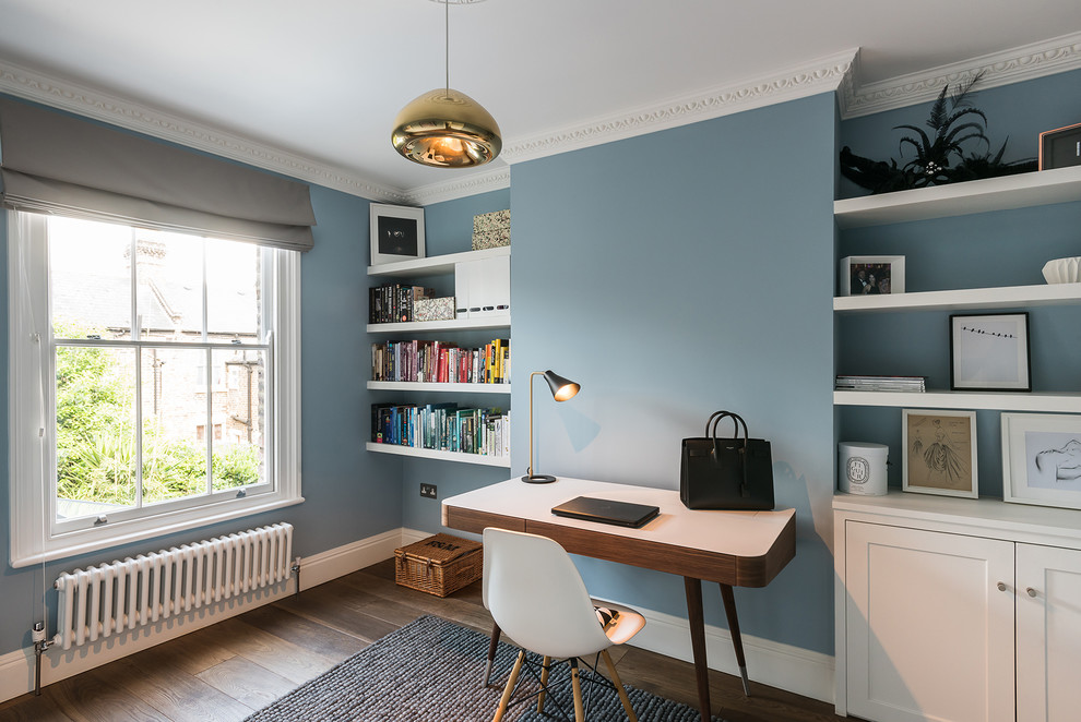 Classic study in London with blue walls, medium hardwood flooring and a freestanding desk.