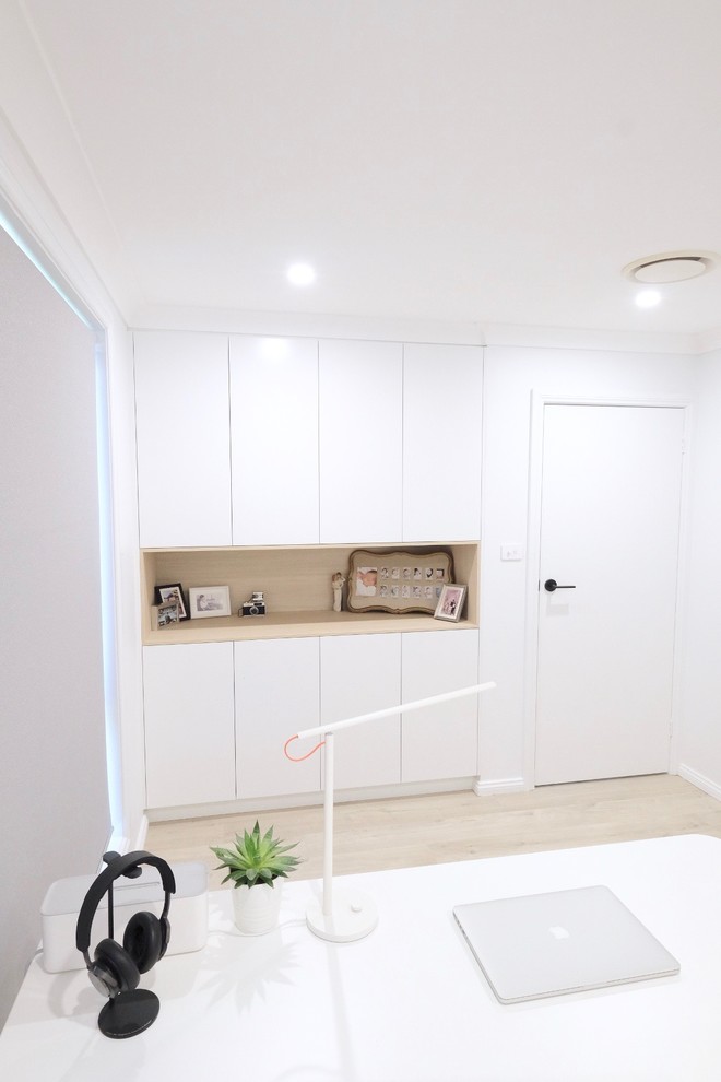 Immagine di un ufficio minimalista di medie dimensioni con pareti bianche, pavimento in laminato, scrivania autoportante e pavimento beige