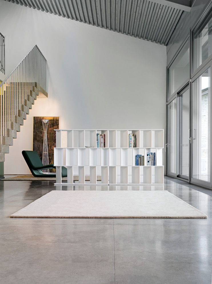 Idée de décoration pour un grand bureau design avec une bibliothèque ou un coin lecture, un mur blanc, sol en béton ciré et un sol beige.