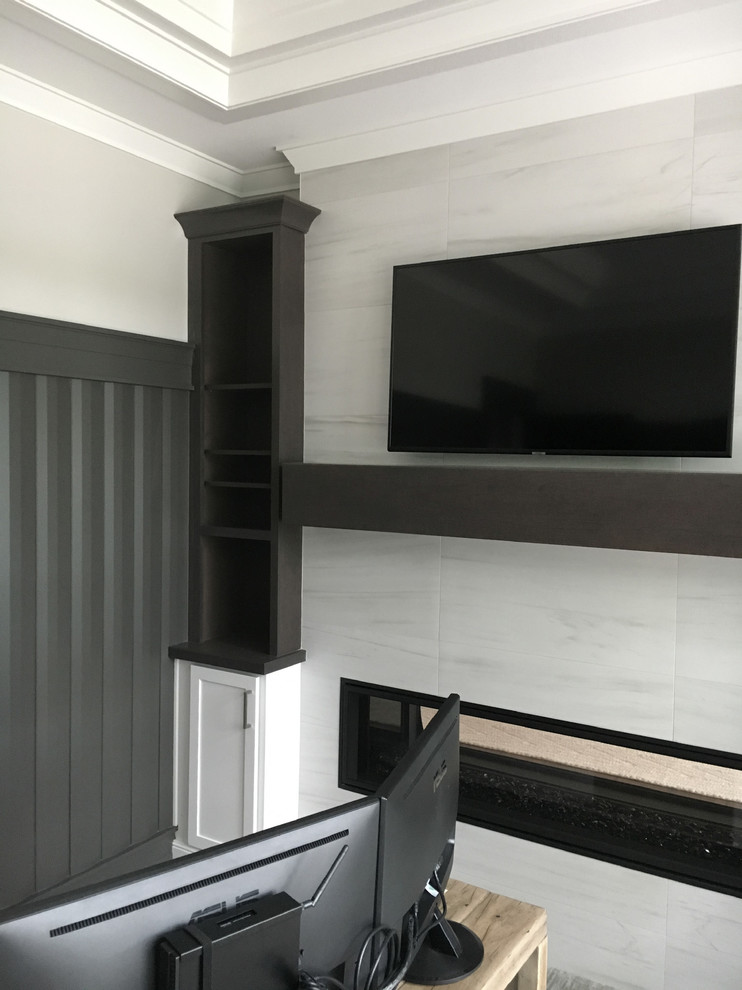 Modelo de despacho minimalista grande con paredes grises, moqueta, chimenea lineal, marco de chimenea de baldosas y/o azulejos, escritorio independiente y suelo gris
