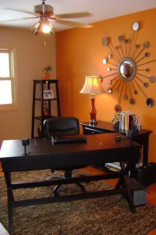 Inredning av ett klassiskt mellanstort hemmabibliotek, med orange väggar och ett fristående skrivbord