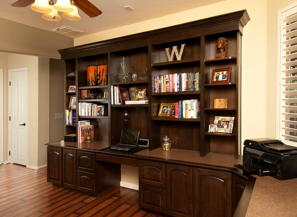 Cette photo montre un bureau sud-ouest américain de taille moyenne avec un sol en bois brun, aucune cheminée, un bureau intégré et un mur blanc.