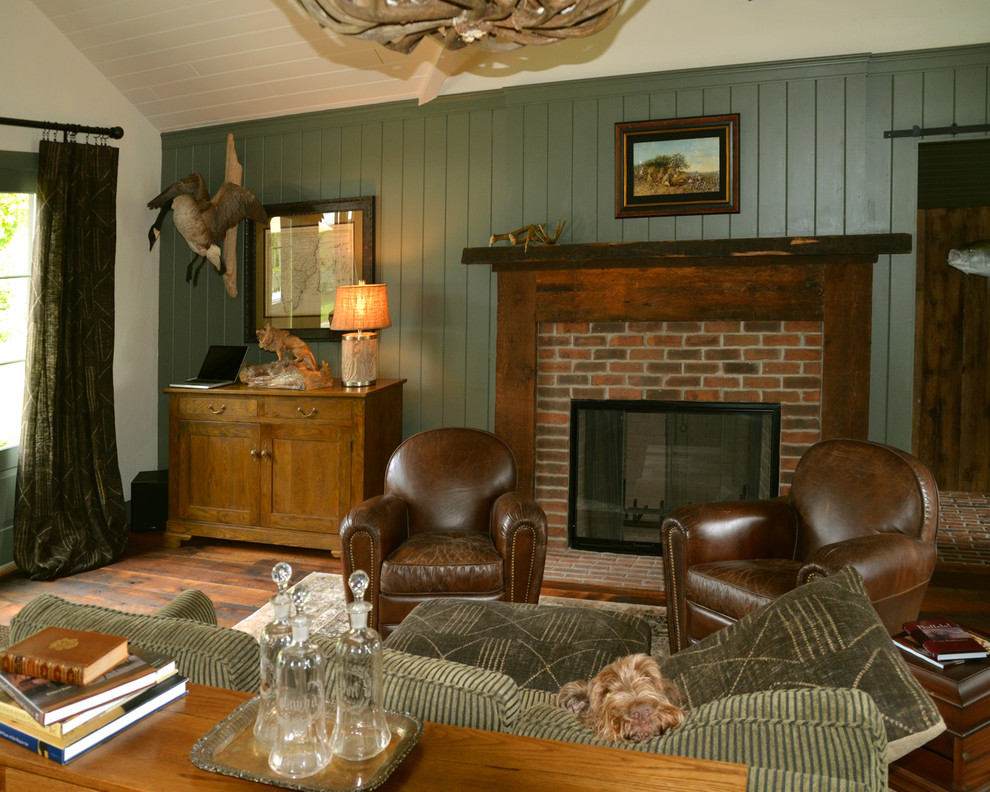 Cette image montre un grand bureau traditionnel avec un mur vert, un sol en bois brun, une cheminée standard, un manteau de cheminée en brique, un bureau indépendant et un sol marron.
