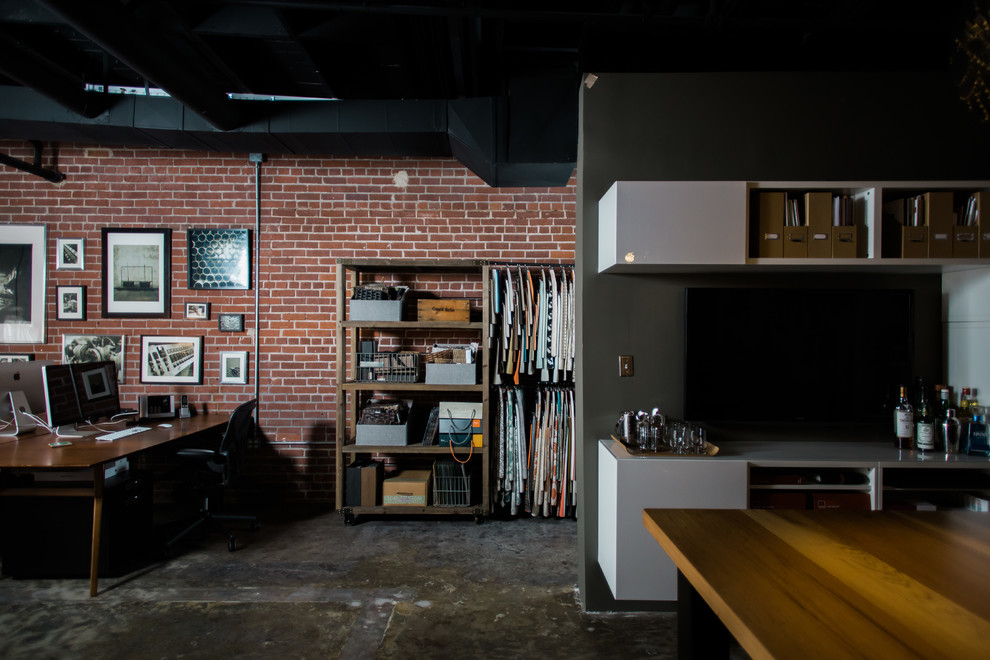 Immagine di un atelier industriale di medie dimensioni con pareti grigie, pavimento in cemento e scrivania autoportante