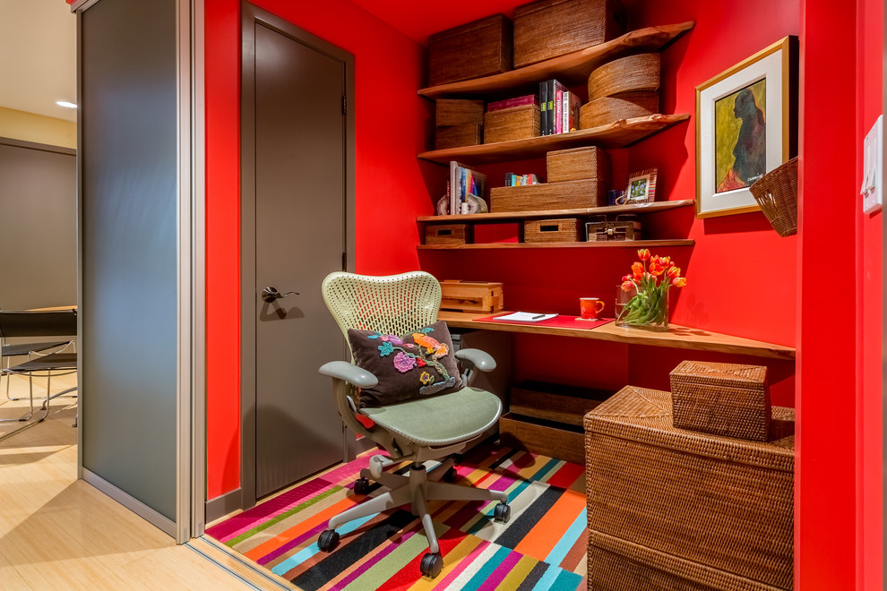 シアトルにあるラグジュアリーな小さなコンテンポラリースタイルのおしゃれな書斎 (赤い壁、カーペット敷き、造り付け机、マルチカラーの床) の写真