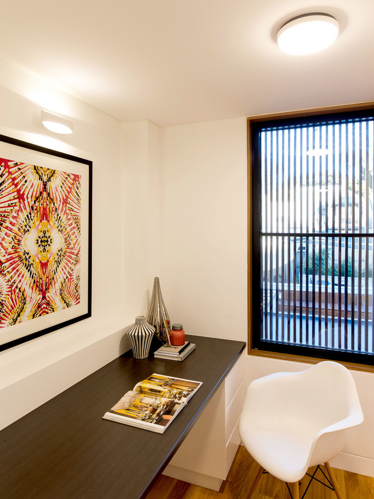 Kleines Modernes Arbeitszimmer ohne Kamin mit Einbau-Schreibtisch, Arbeitsplatz, weißer Wandfarbe und braunem Holzboden in Sydney