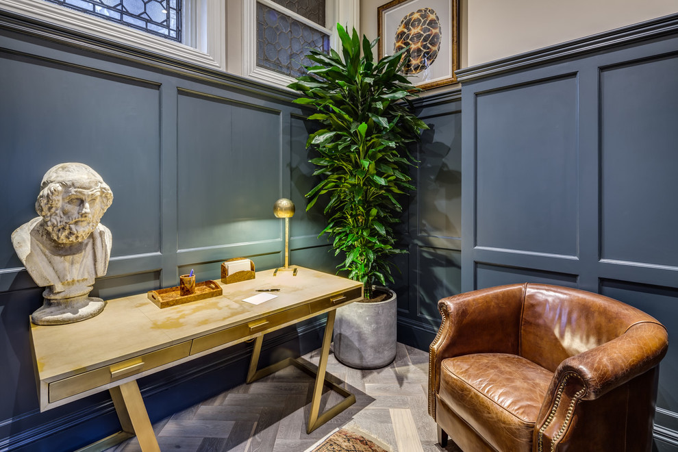 Ejemplo de despacho actual grande sin chimenea con paredes azules, suelo de madera en tonos medios y escritorio independiente