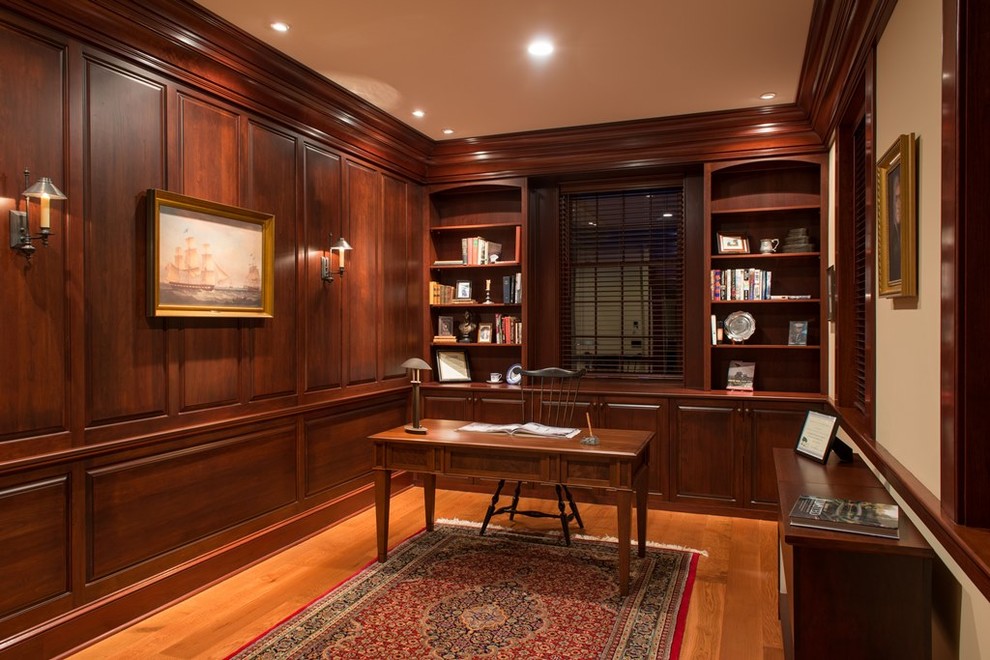 Klassisches Arbeitszimmer ohne Kamin mit Arbeitsplatz, brauner Wandfarbe, braunem Holzboden und freistehendem Schreibtisch in Boston