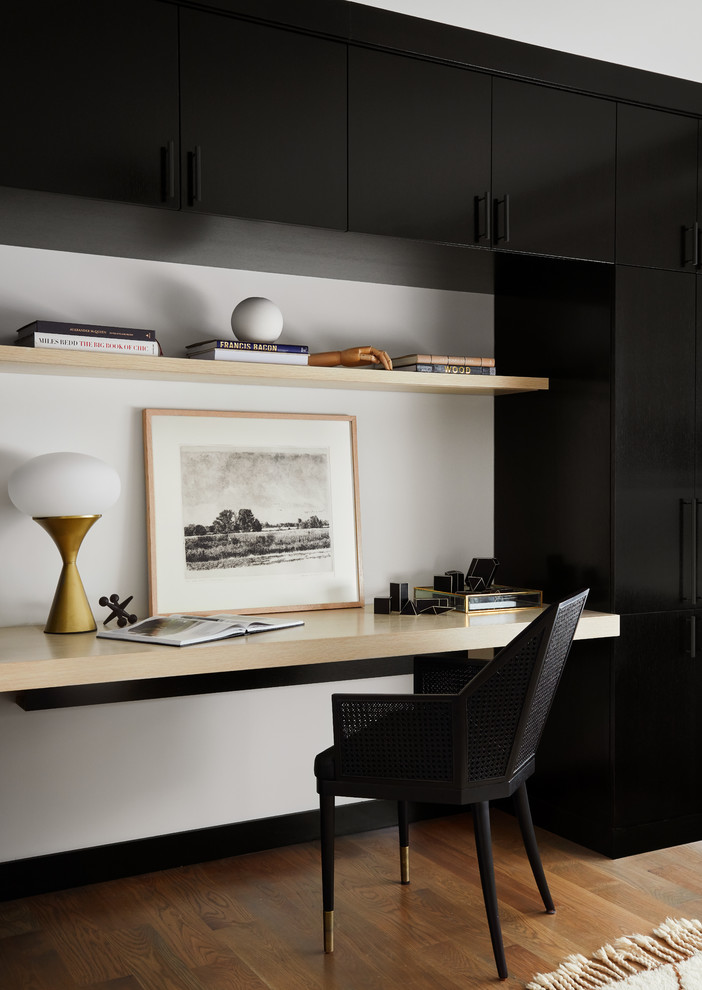 Diseño de despacho contemporáneo de tamaño medio con paredes blancas, suelo de madera en tonos medios y escritorio empotrado