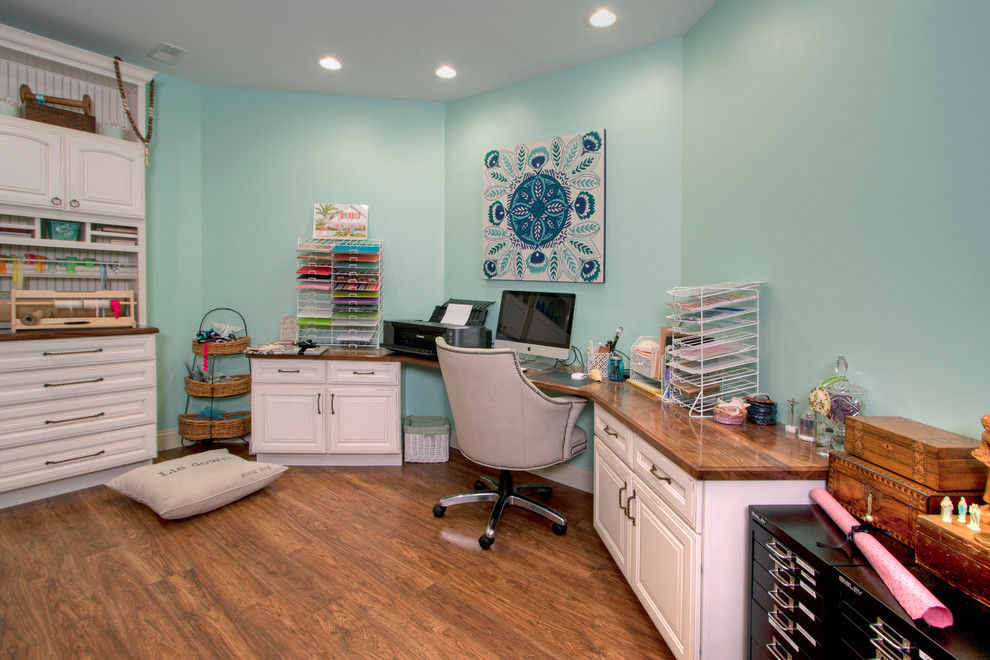 Foto de sala de manualidades clásica grande con paredes azules, suelo de madera en tonos medios y escritorio empotrado