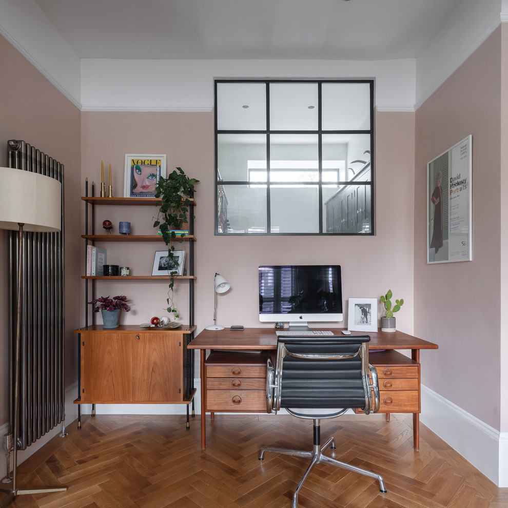 Inspiration for a mid-sized transitional freestanding desk medium tone wood floor and brown floor home office remodel in London with pink walls