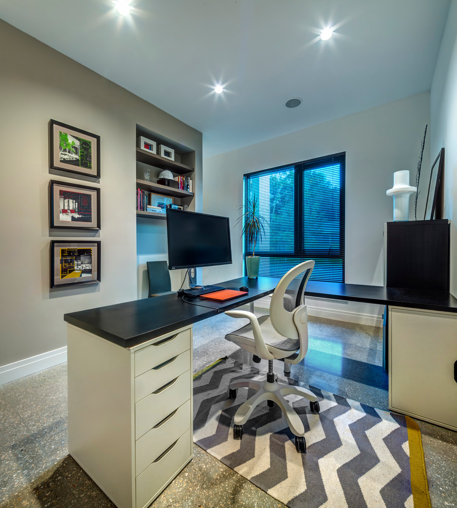 На фото: кабинет среднего размера в стиле модернизм с серыми стенами, бетонным полом и отдельно стоящим рабочим столом без камина с